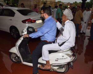 जलभराव में अपनी गाड़ी फंसने पर सपा के निजामाबाद विधायक दूसरे की स्कूटी से निकलते हुए।