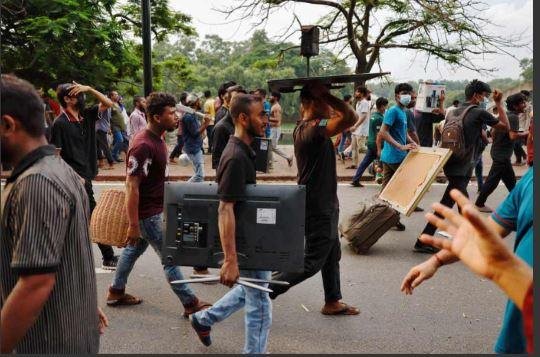 ढाका में शेख हसीना के आवास से कंप्यूटर और फर्नीचर लूटकर ले जाते प्रदर्शनकारी