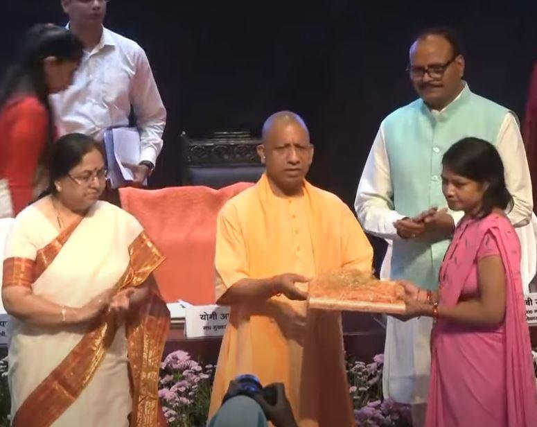 लखनऊ के पोषण माह कार्यक्रम में आंगनबाड़ी वर्कर को सम्मानित करते सीएम योगी। 