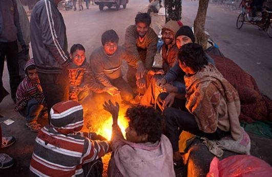ठंड में अलाव तापते लोग।